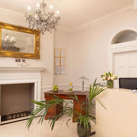Montcalm Brewery Townhouse Hotel London Exterior photo The photo shows a stylish reception area. There is a decorative chandelier hanging from the ceiling, providing elegant lighting. A large, ornate mirror is mounted on the wall beside the fireplace, which features a simple, classic design. In front of 